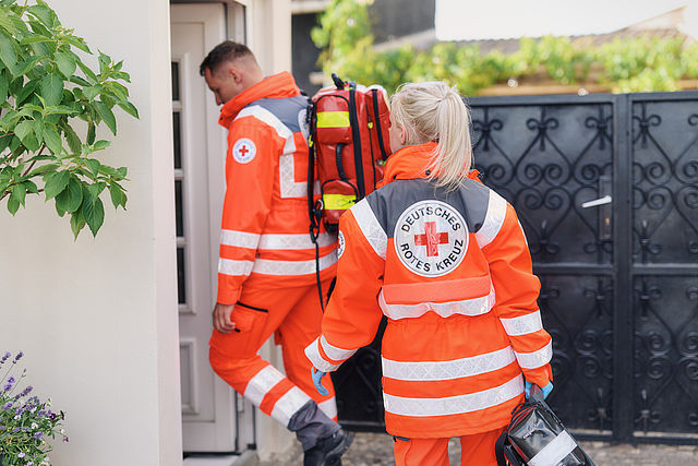 Rettungsdienst am Einsatzort. Rettungssanitäter gehen in ein Haus
